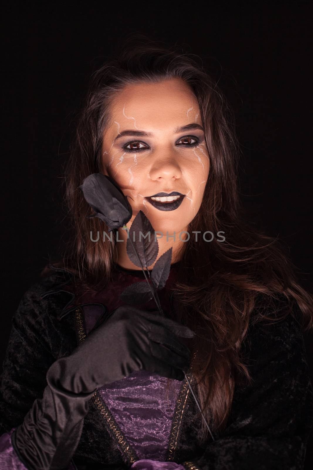 Witch with an evil face over black background . Halloween costume.