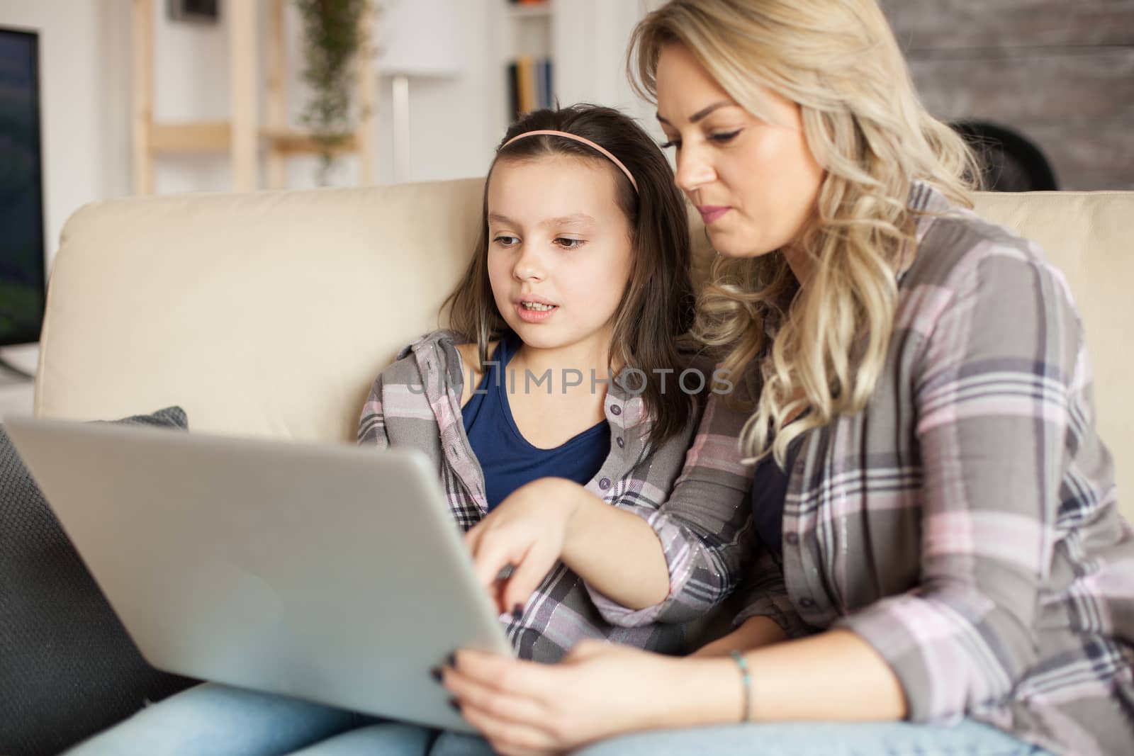 Mother and daughter using laptop with wireless technology for surfing on the internet.