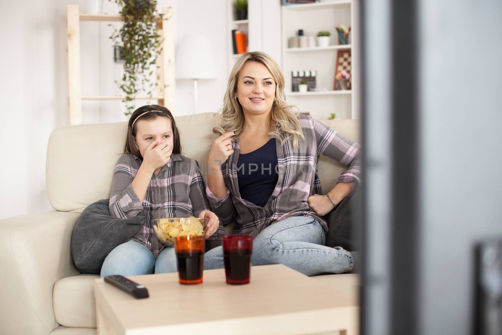 Young mother and her little girl watching movies by DCStudio