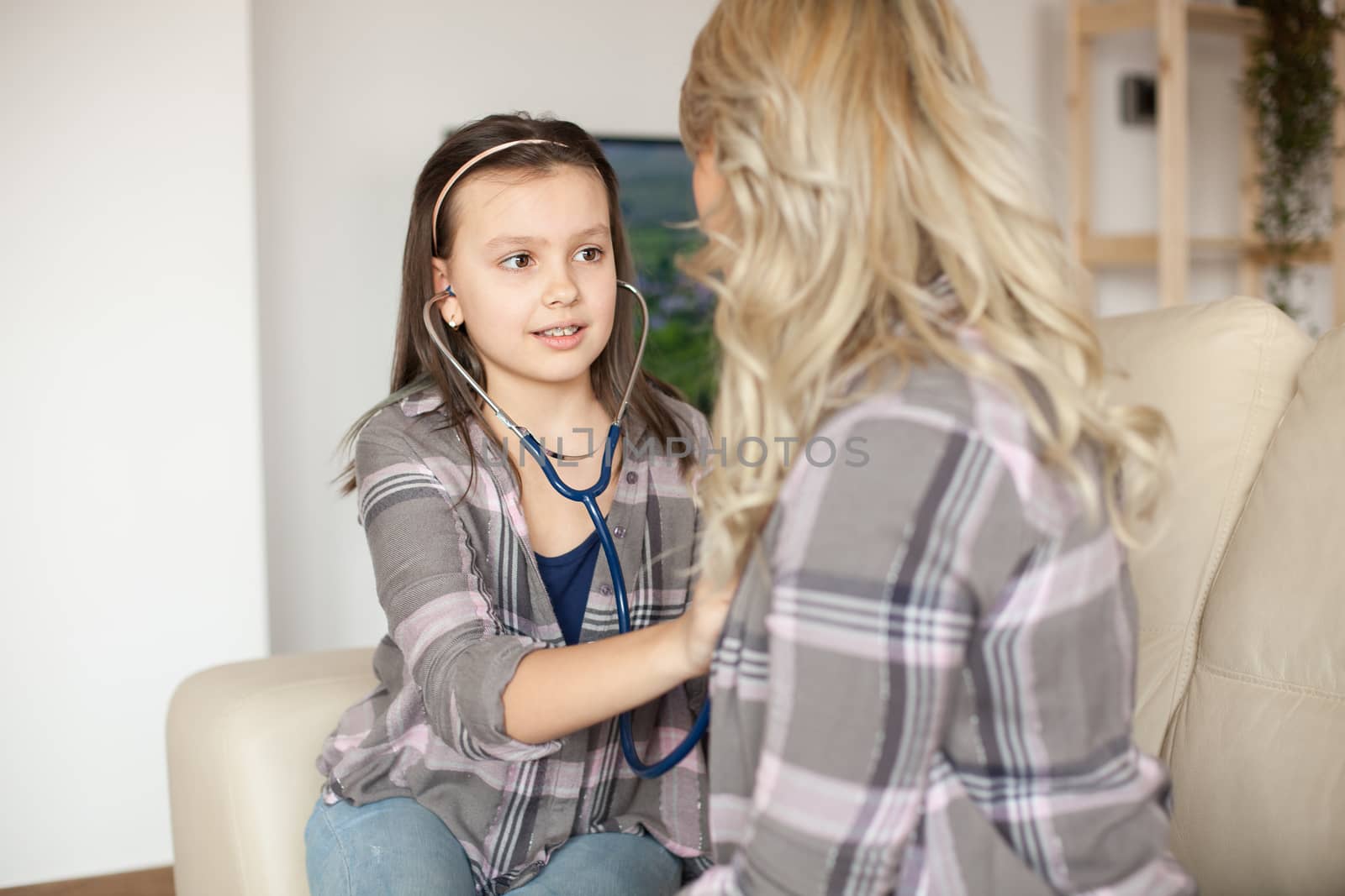 Worried little girl using stethoscope to help her mother with breathing problem. Medical care.