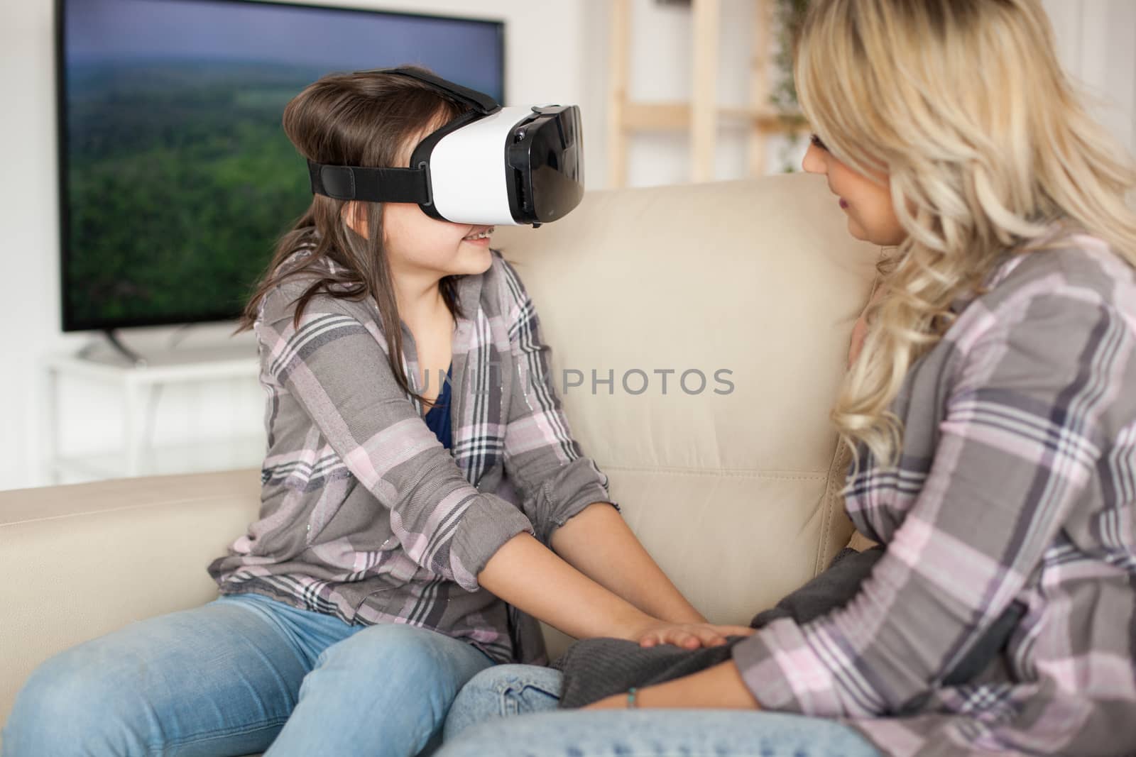 Happy little girl enjoying her virtual reality headset. Young mother.