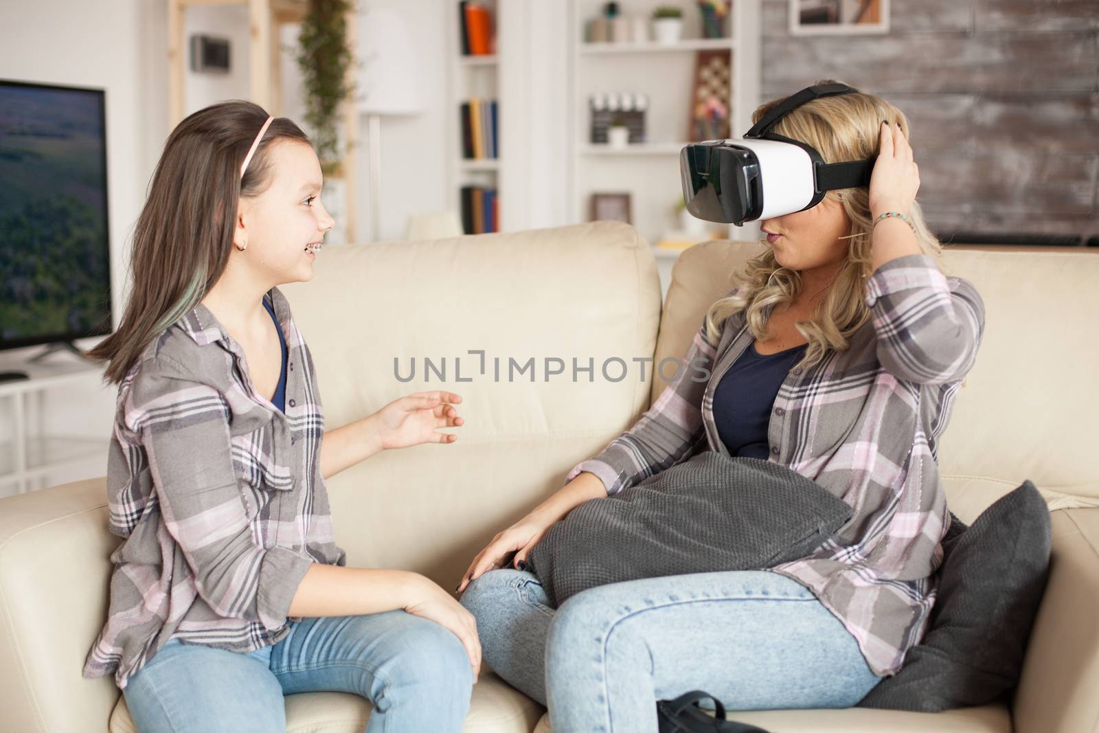 Excited little girl about her mother using virtual reality headset.