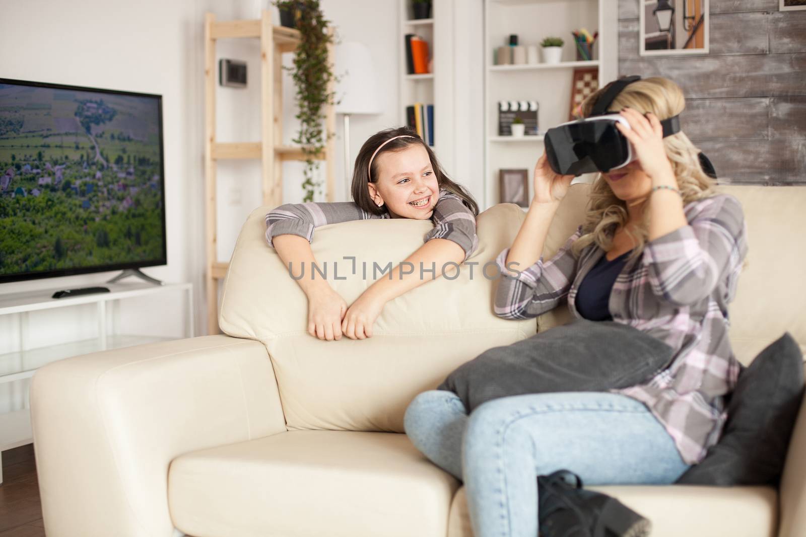 Little girl with braces smiling while her mother is amazed by virtual reality goggles.