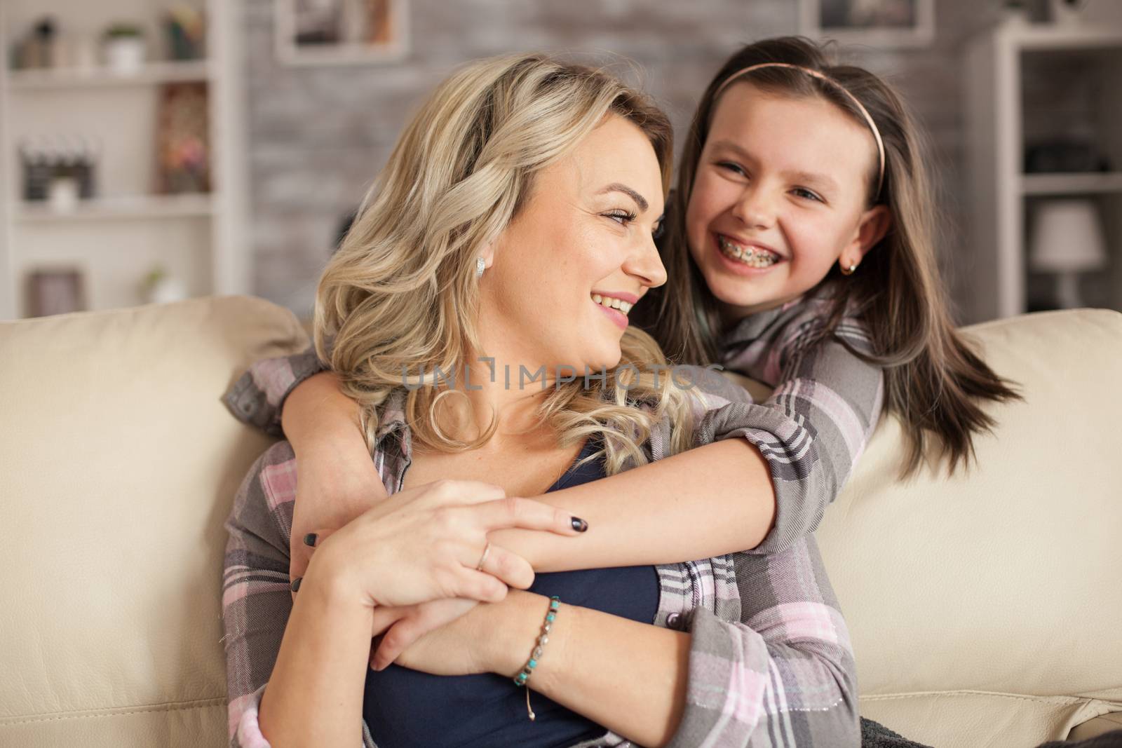 Adorable little girl with braces having a big smile while hugging her mother.