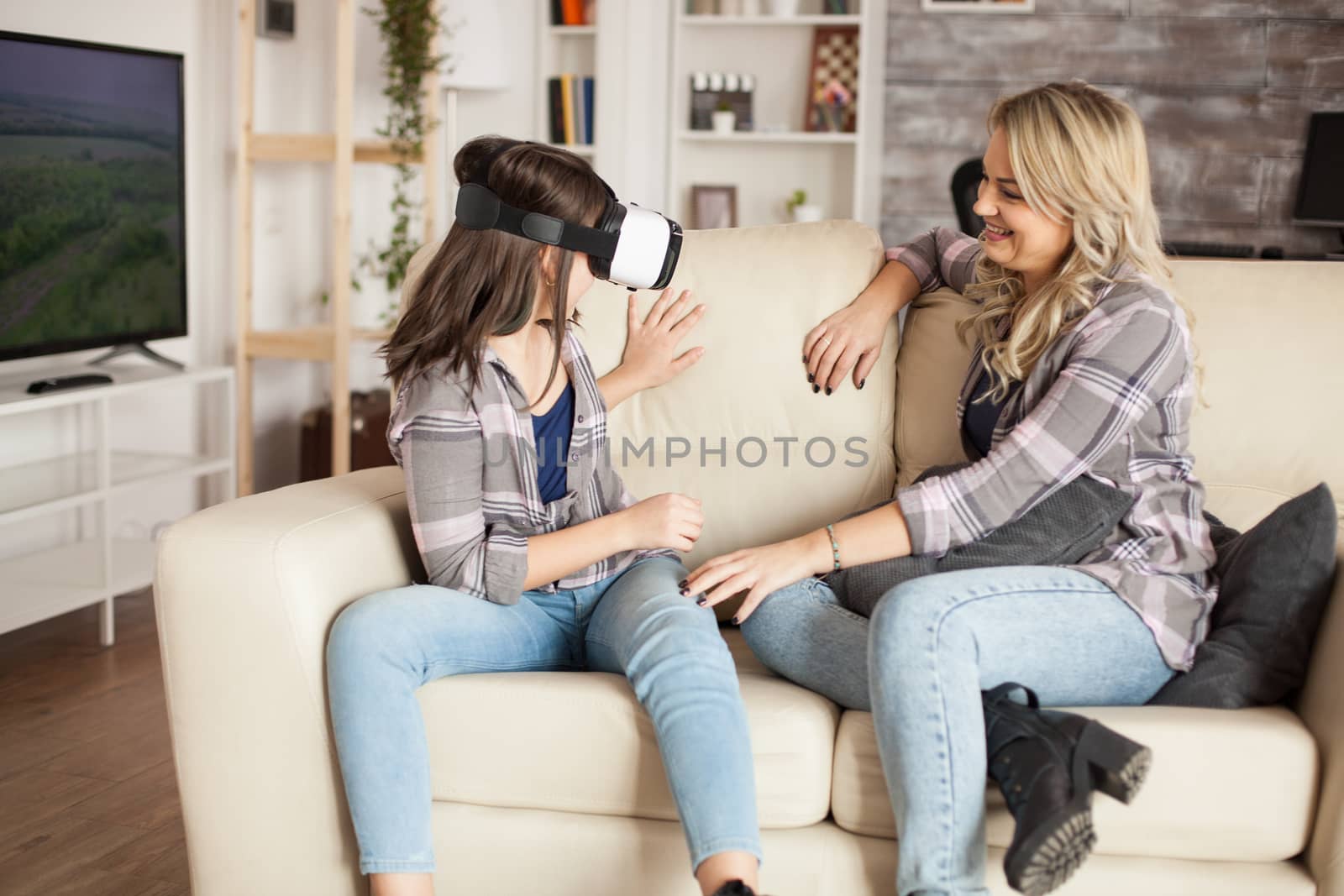 Young mother looking at her little girl having fun with virtual reality headset. Modern motherhood.