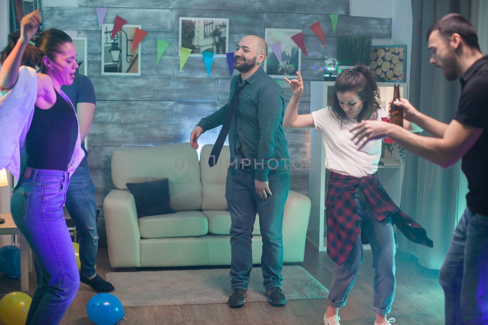 Attractive young man with tie dancing with his friend at a party.