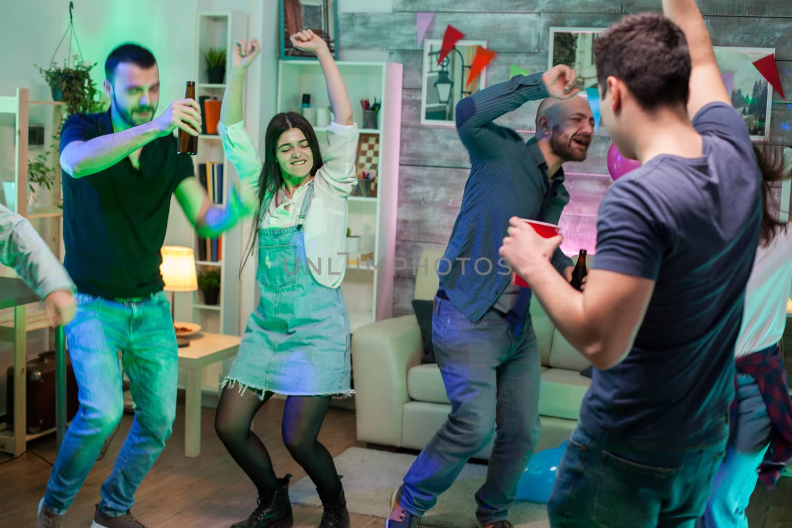 Excited group of friends dancing at a disco party to celebrate the birthday of a friend.