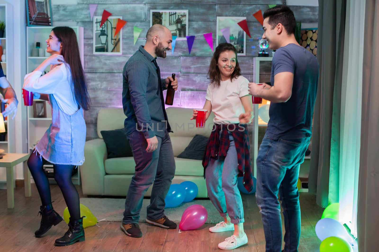 Cheerful young woman having fun and dancing with her friends at a party listening funky music.