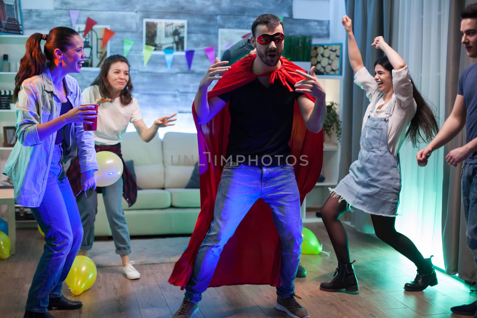 Group of friends looking at young man dressed up in super hero costume at party.