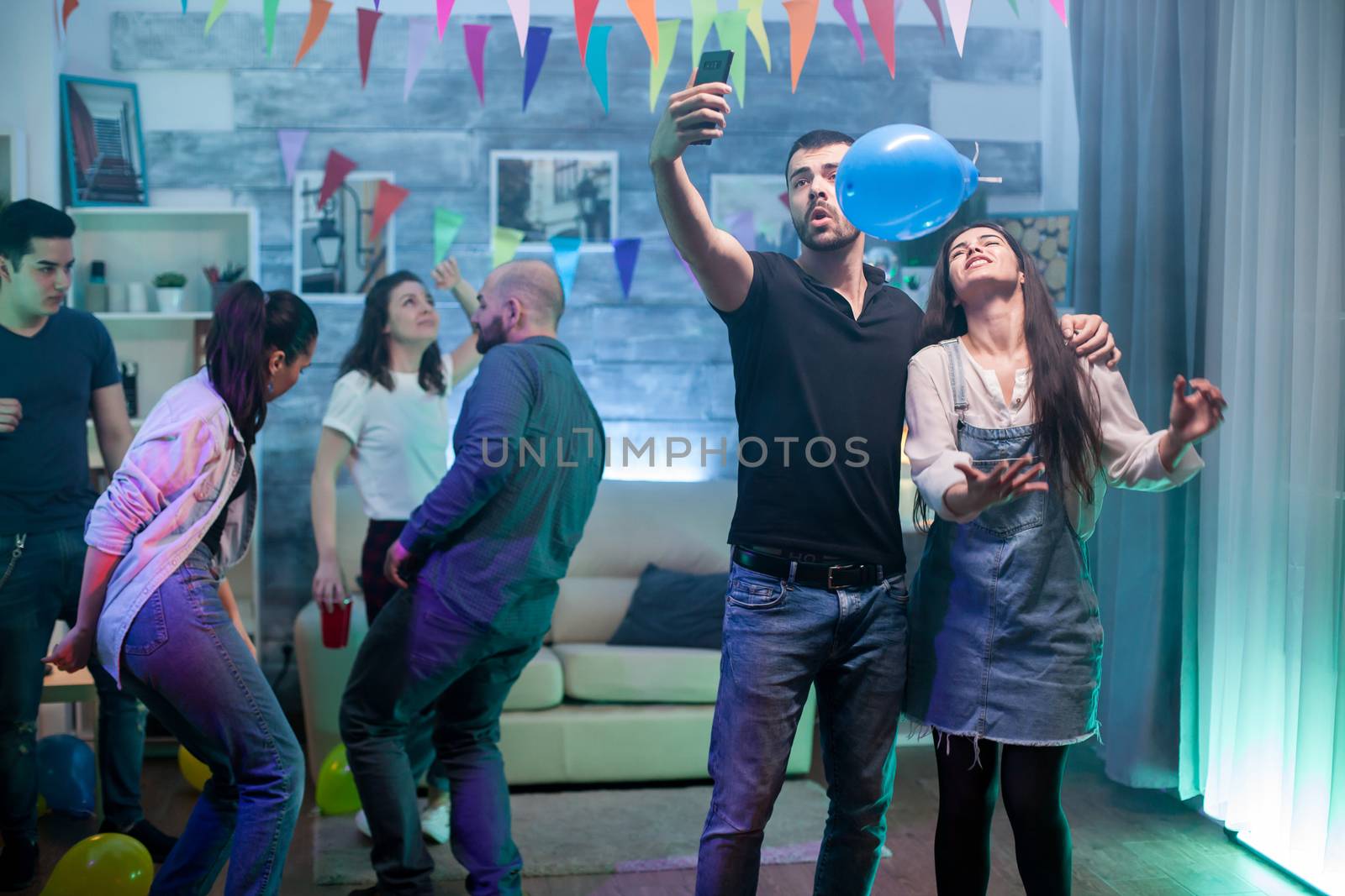 Smiling man and woman taking a selfie while having fun at a party.