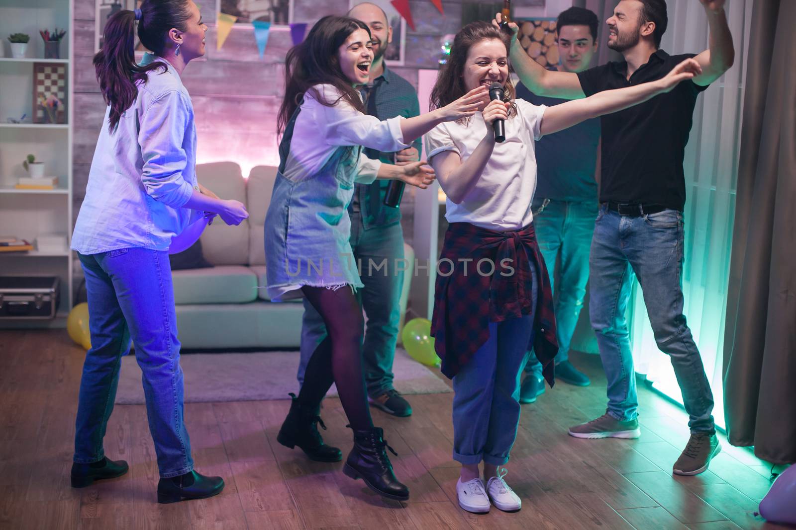 Group of young people dancing and beautiful young woman singing on microphone.