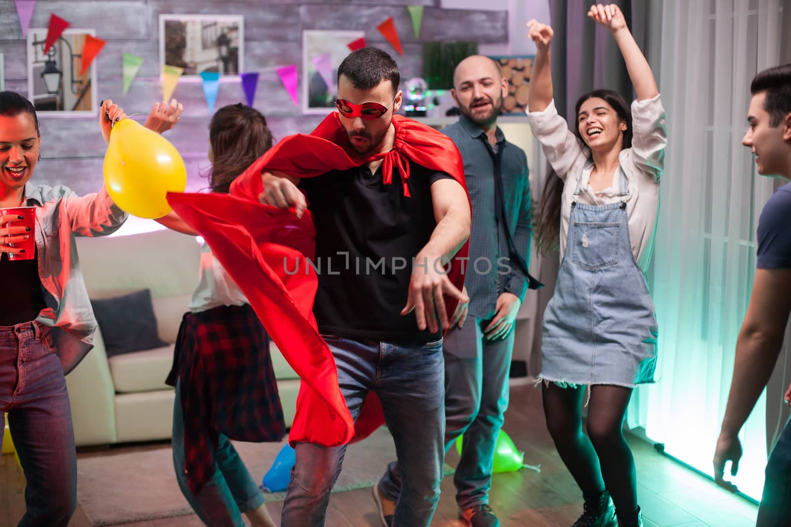 Handsome man in superhero costume dancing on disco music at friends party.