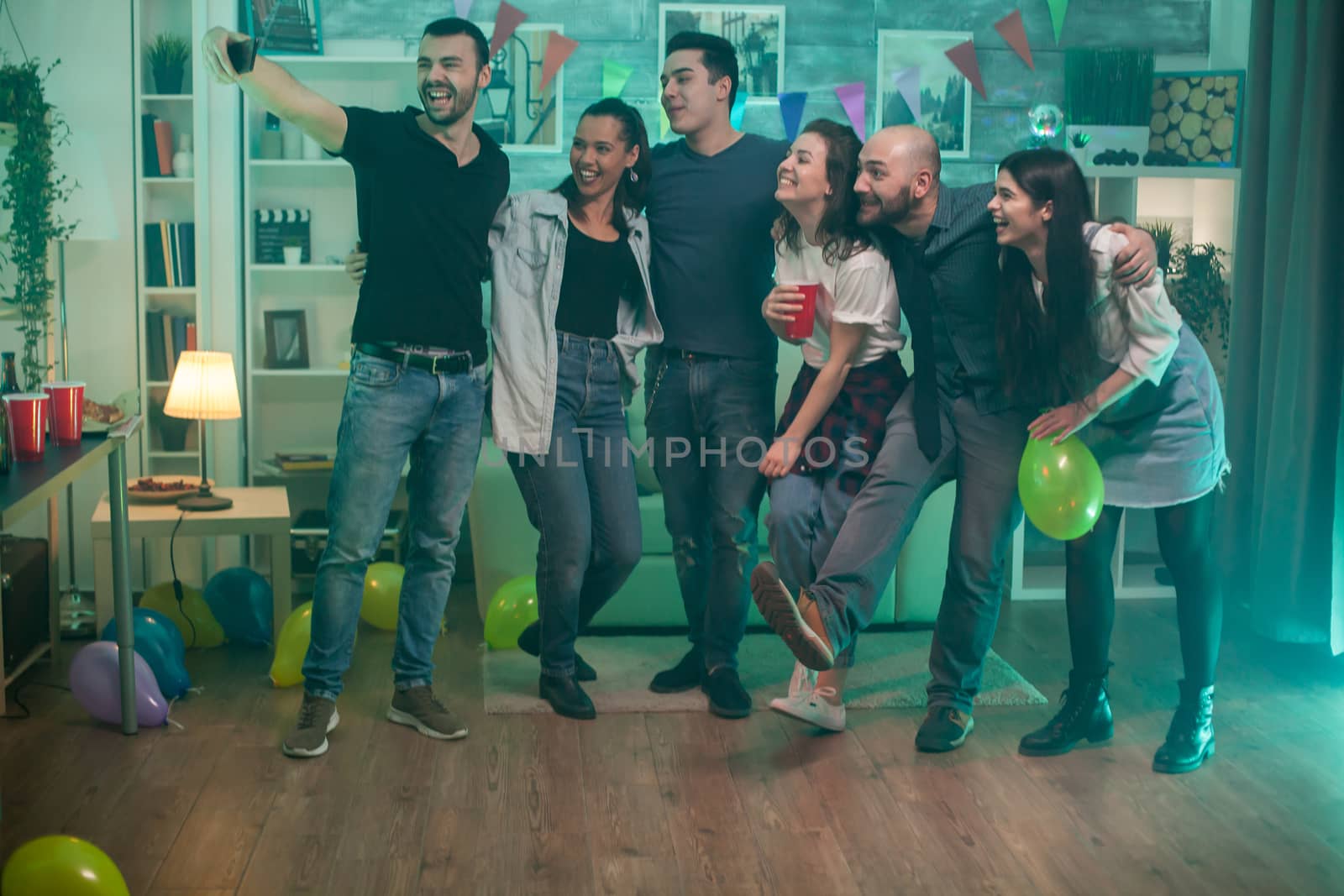 Group of friends having a party in an apartmentand making a selfie.