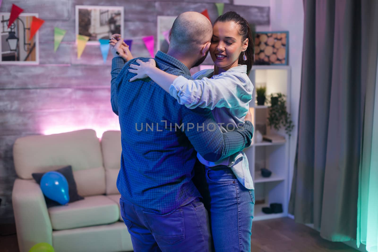 Beautiful young woman with eyes closed while dancing with her boyfriend in new apartment.