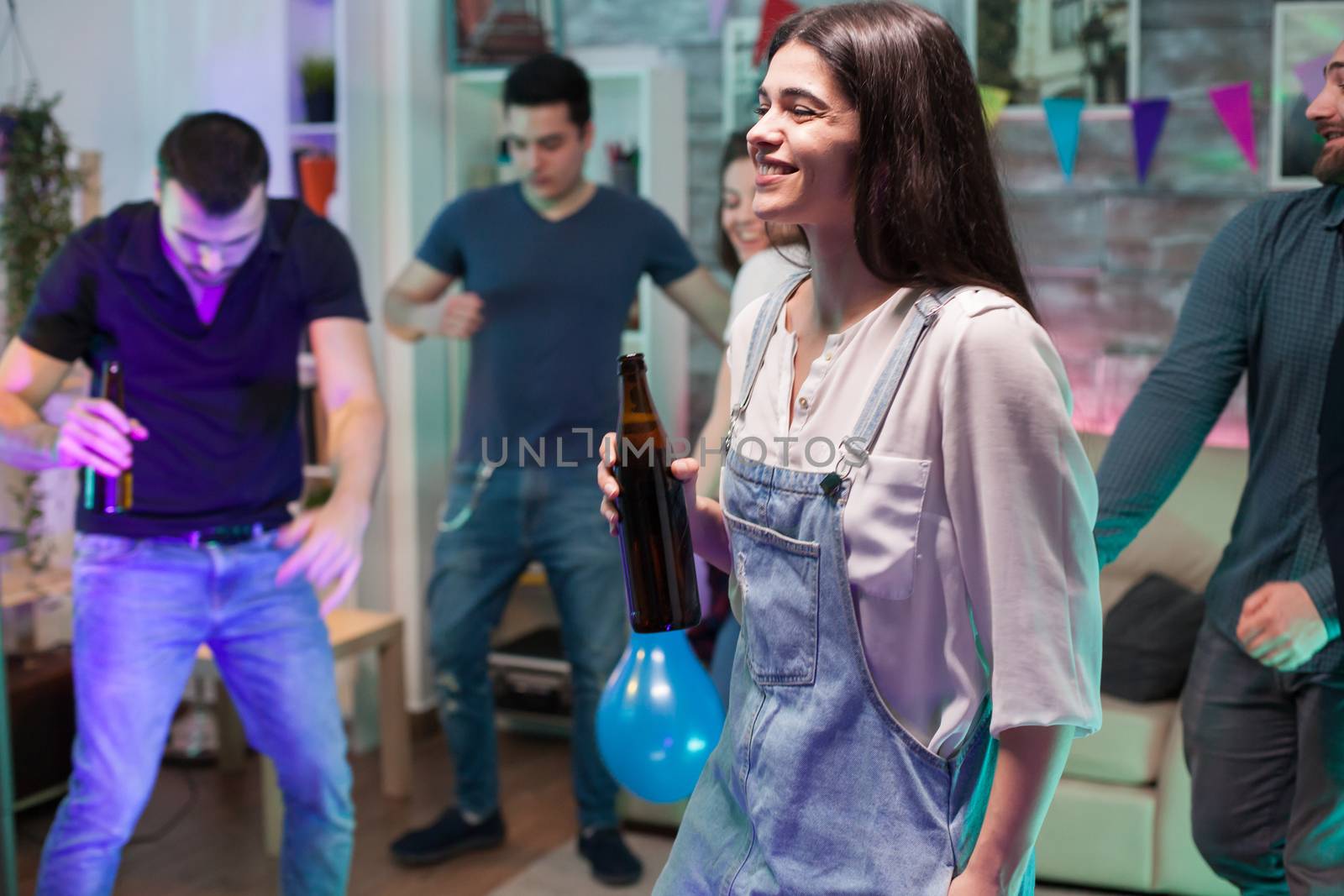 Cheerful young woman smiling and holding a beer bottle by DCStudio