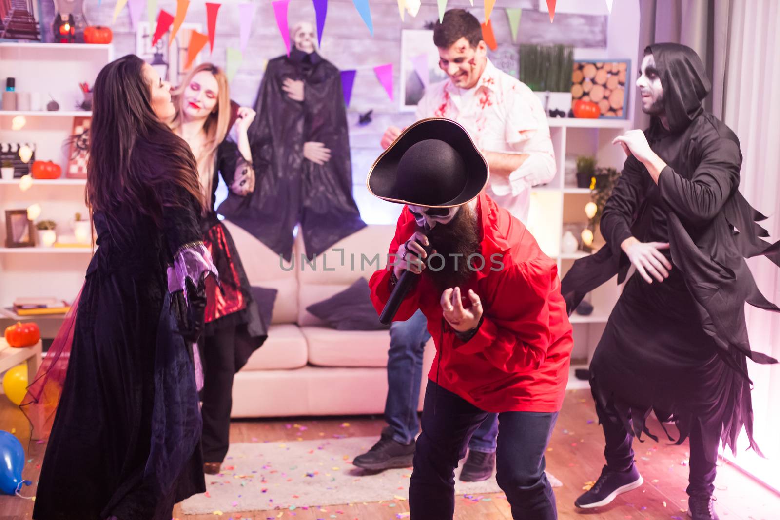 Spooky man dressed up like a pirate doing karaoke at halloween party for his friends.