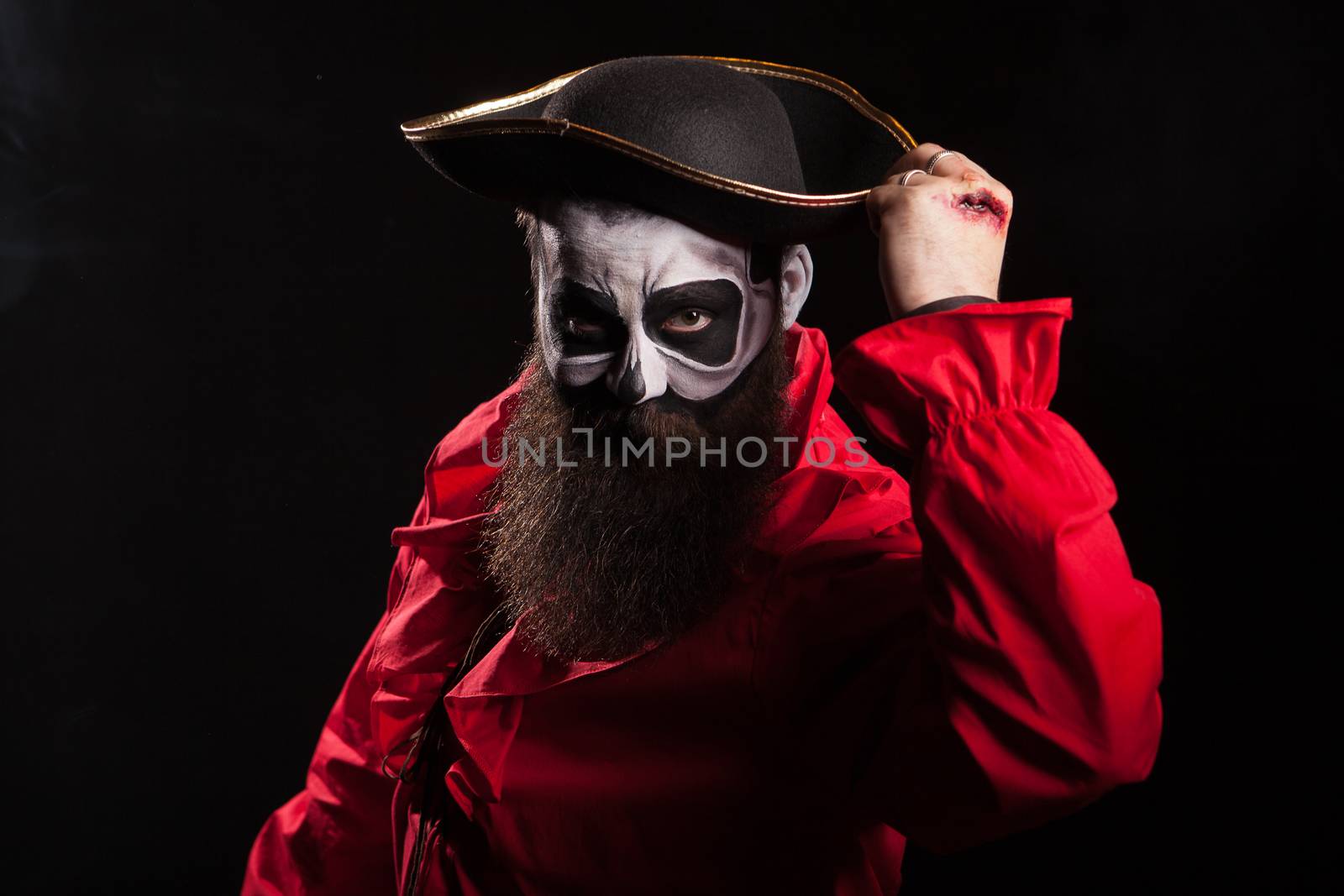 Bearded and spooky medieval pirate with blood on his hands over black background. Halloween disguise.