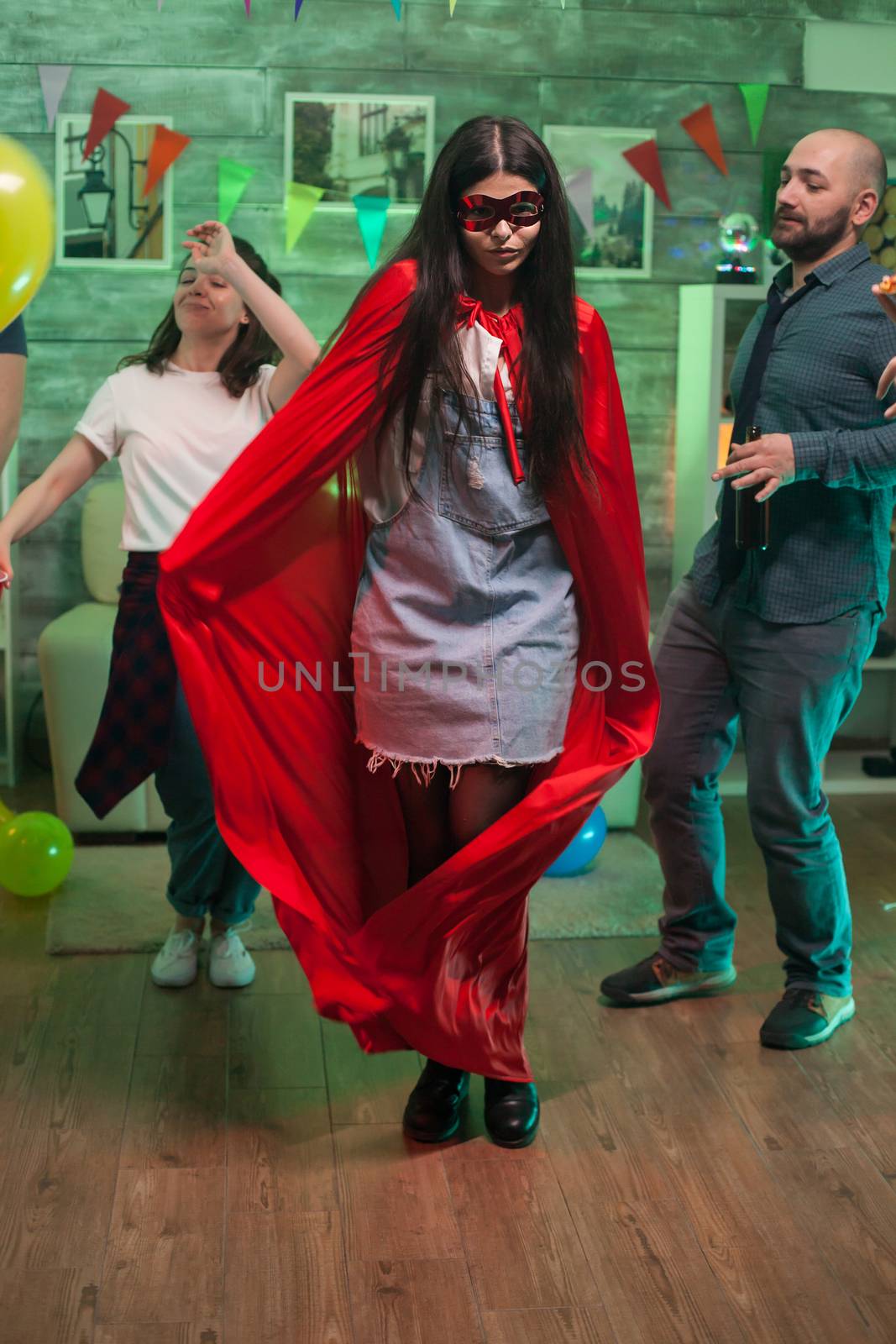 Cheerful young woman dressed up like a superhero at friends party.
