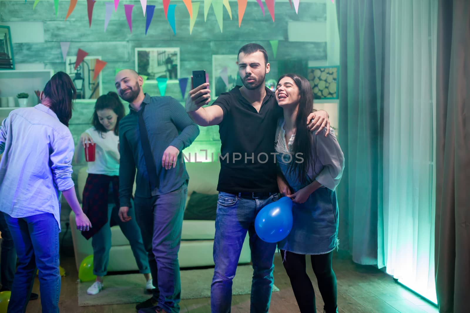 Beautiful woman holding balloon while taking a selfie at a party with her friend.