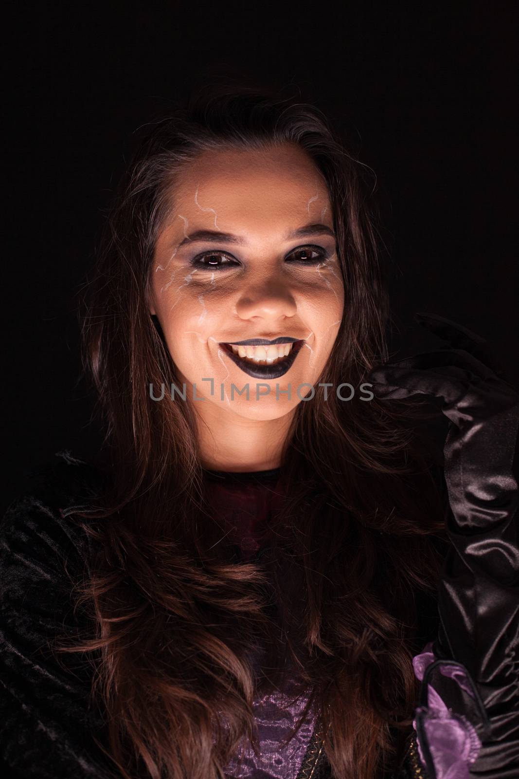 Beautiful woman over black background dressed up like a scary witch for halloween.