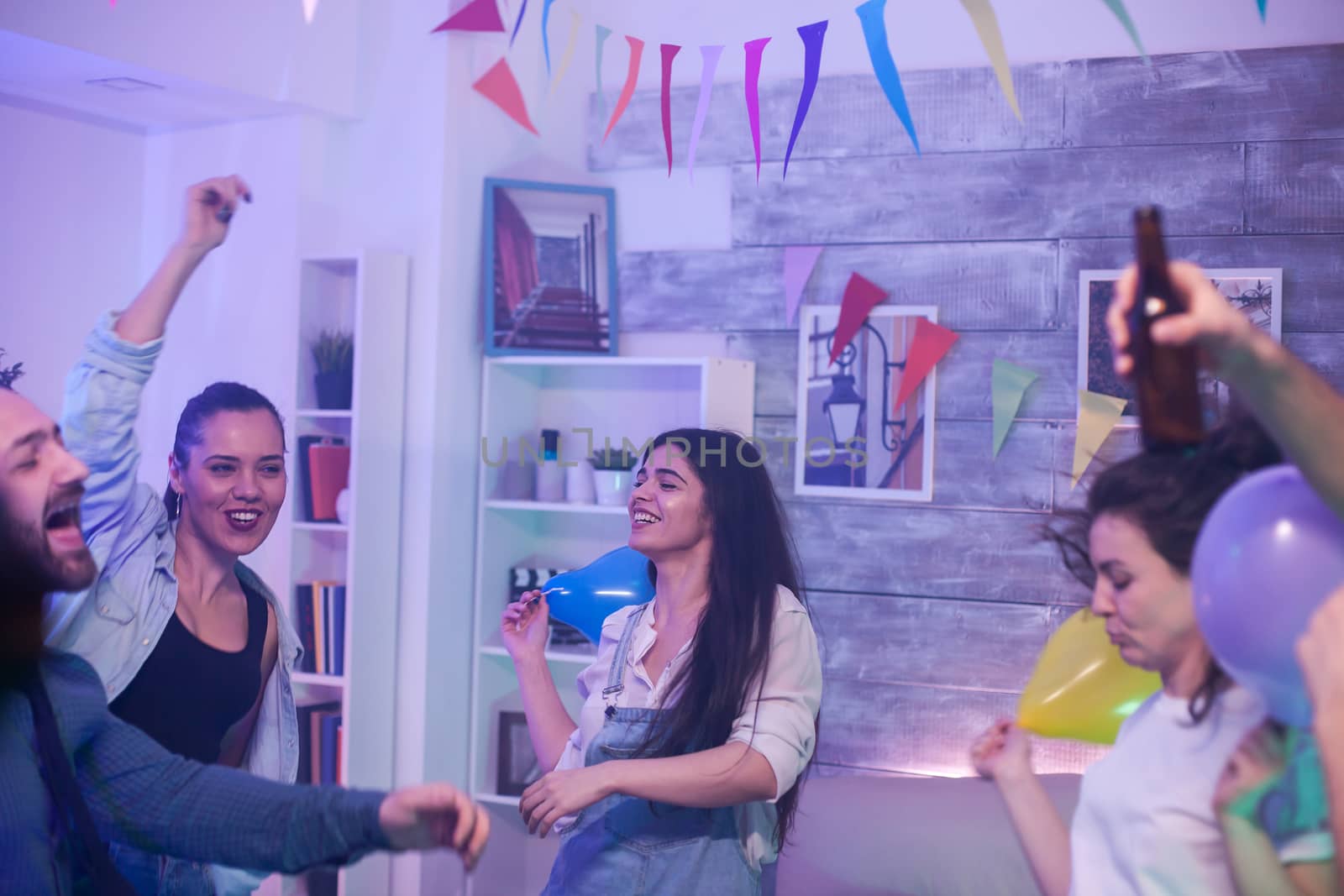 Excited beautiful young woman dancing with her friends at the party.