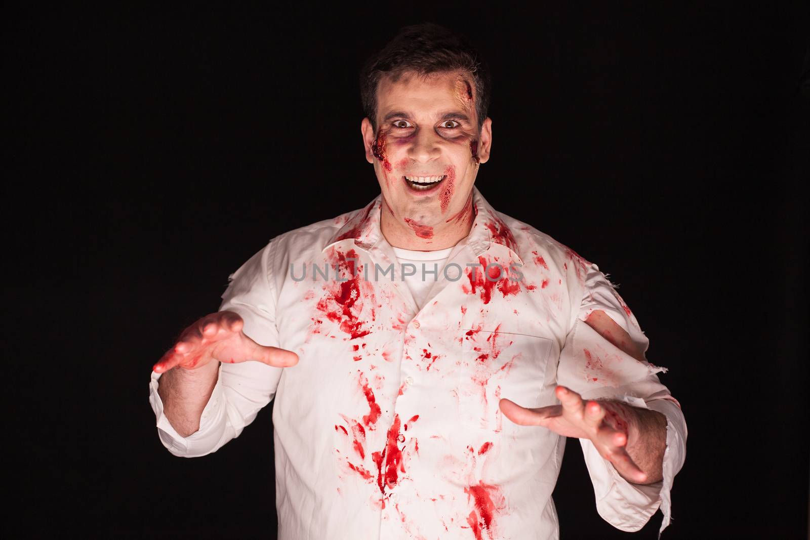 Demon after a massacre with blood on him over black background. Creative makeup.