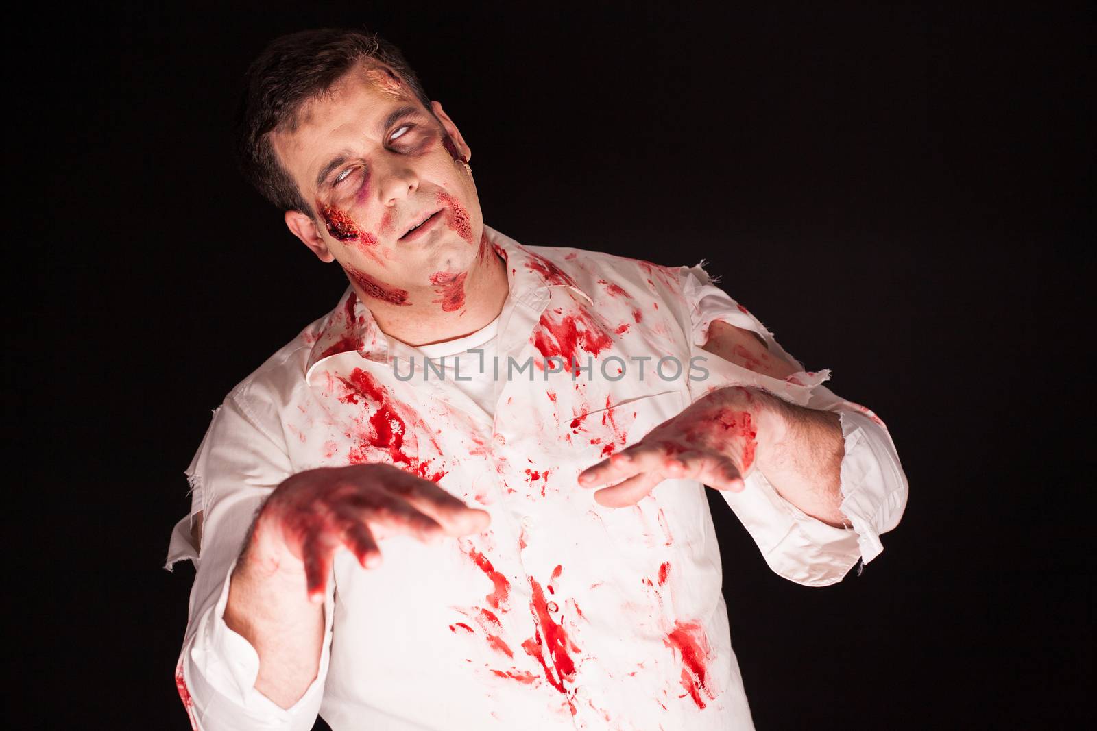 Haunted zombie with blood all on his face over black background.