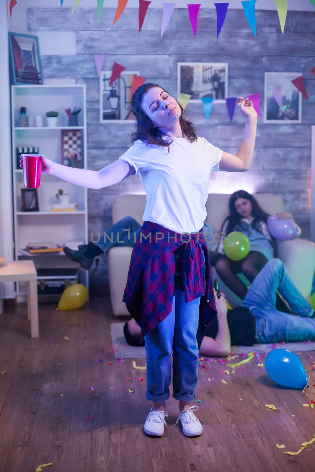 Joyful young woman dancing with a beer cup at a party.