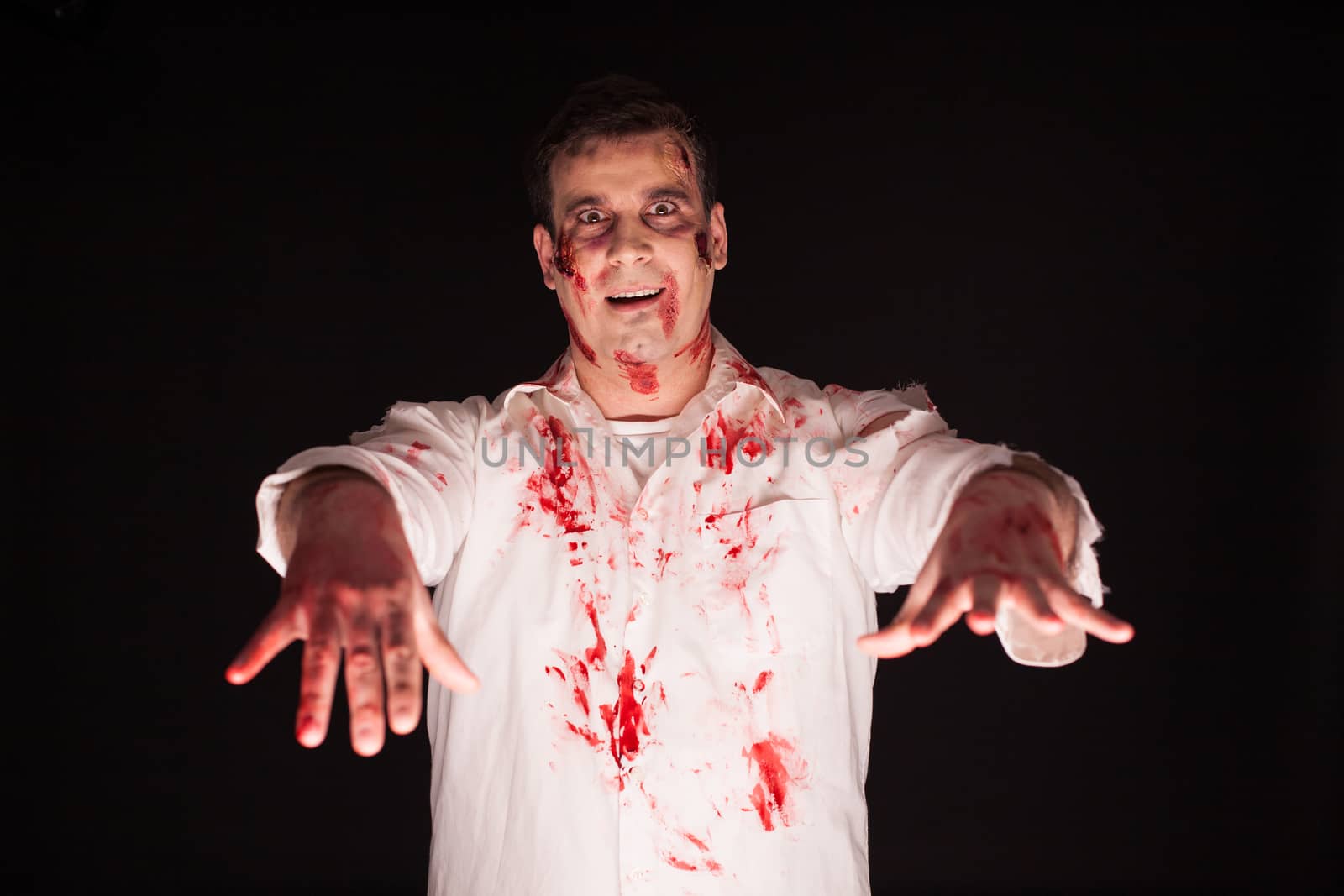 Scary man with bloody hands over black background by DCStudio