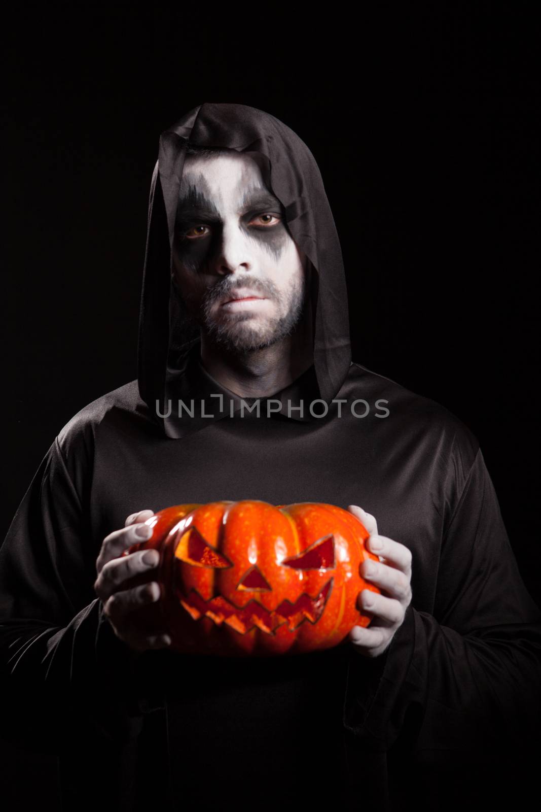 Spooky grim reaper holding a pumpkin over black background by DCStudio