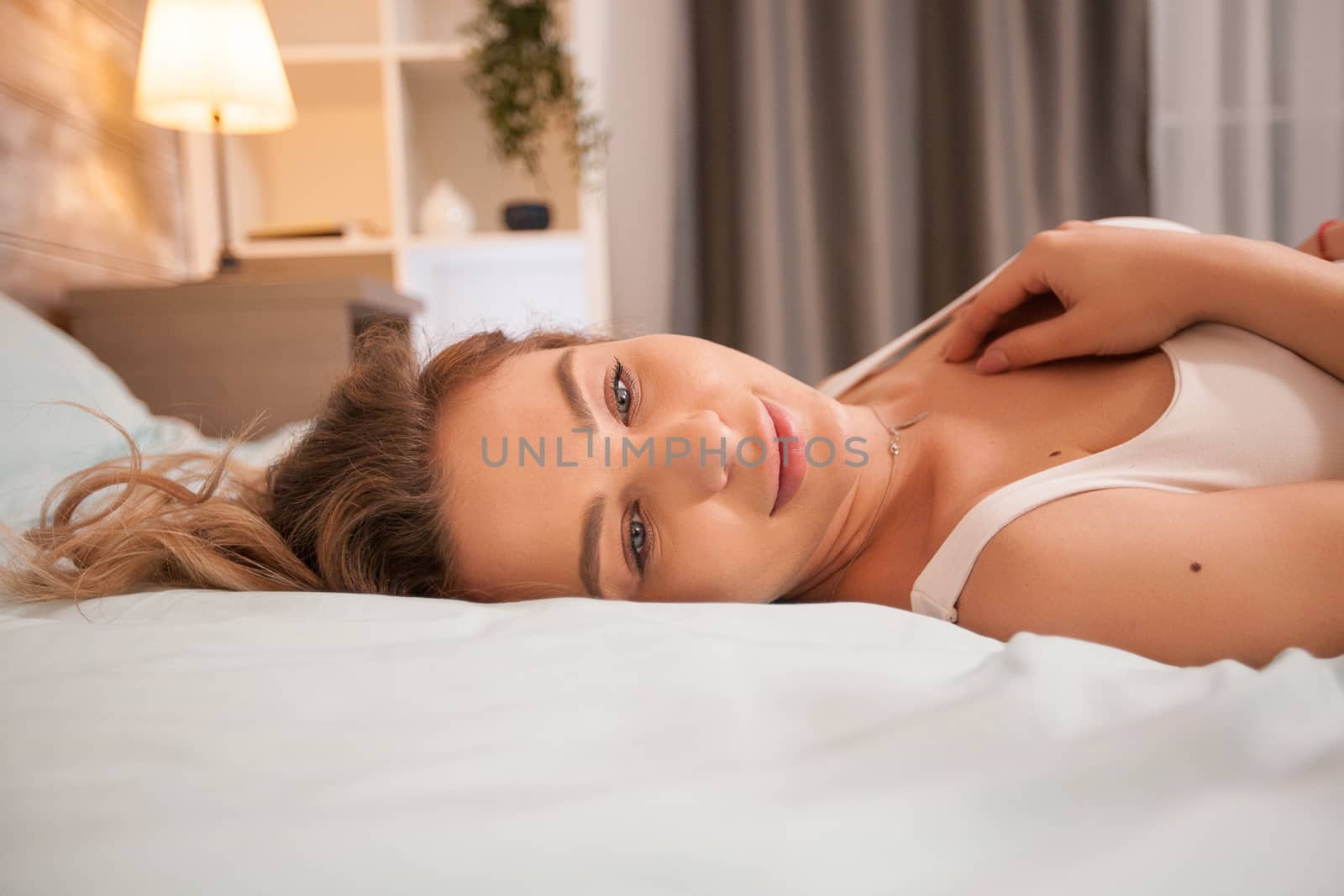 Portrait of beautiful young woman in pajamas at night resting in bed.