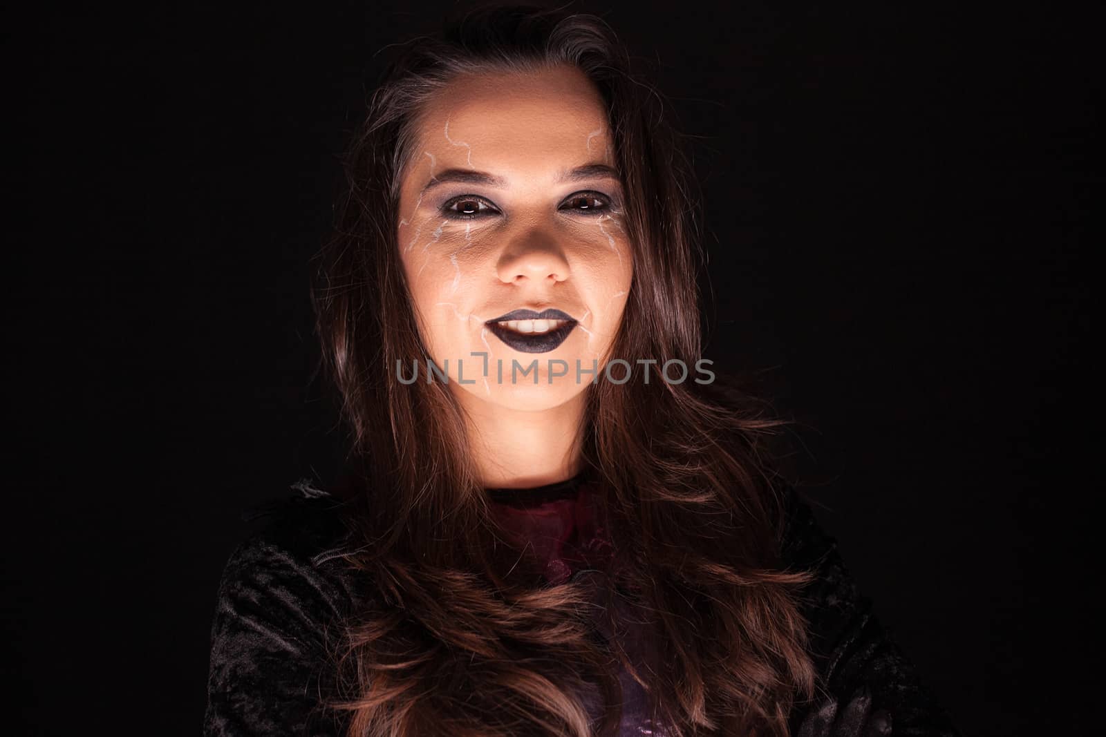 Attractive woman in a witch outfit for halloween looking at the camera over black background.