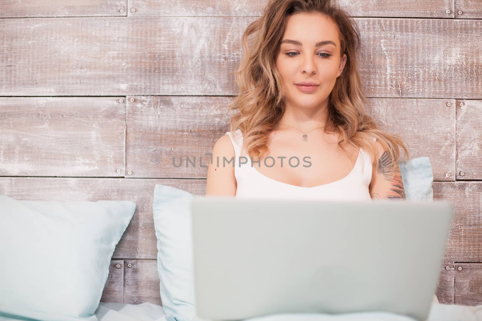 Pretty blonde woman working late at night on her laptop wearing pajamas .