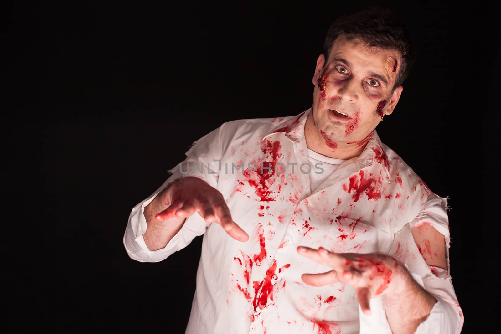 Man wearing a bloody zombie costume over black background by DCStudio