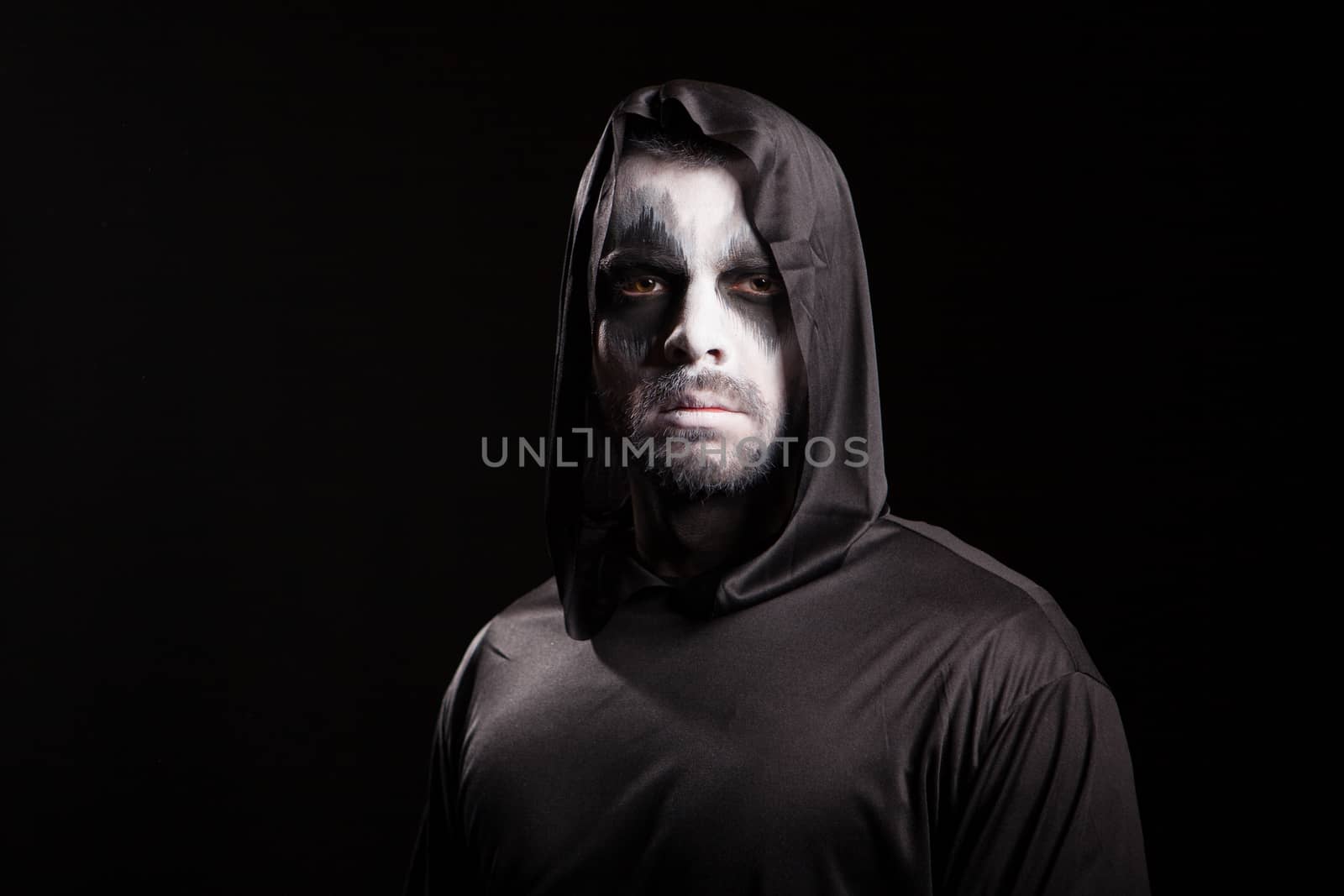 Young man looking serious into the camera dressed up like grim reaper. Halloween costume.