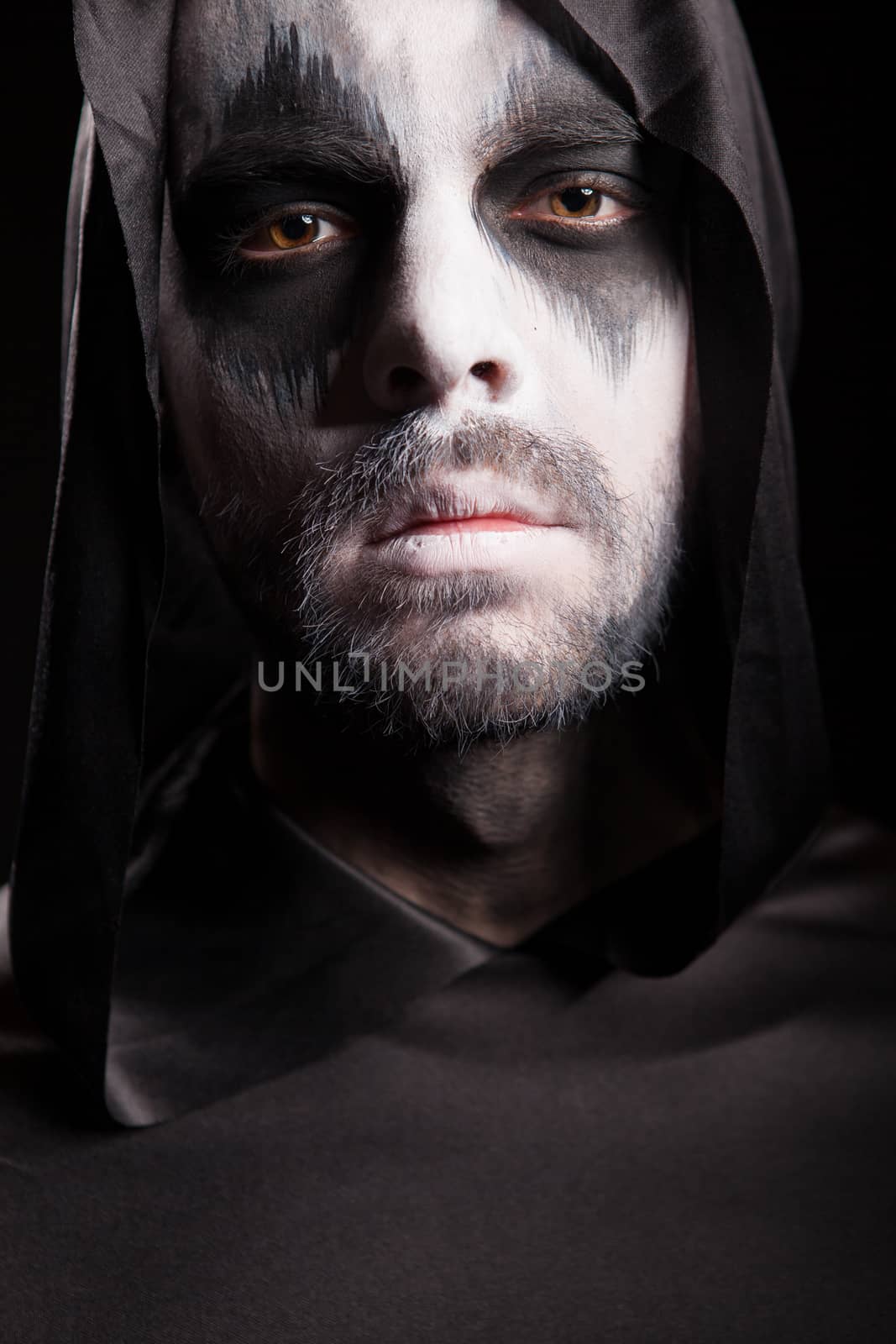 Close up portrait of grim reaper isolated over black background. Halloween costume.