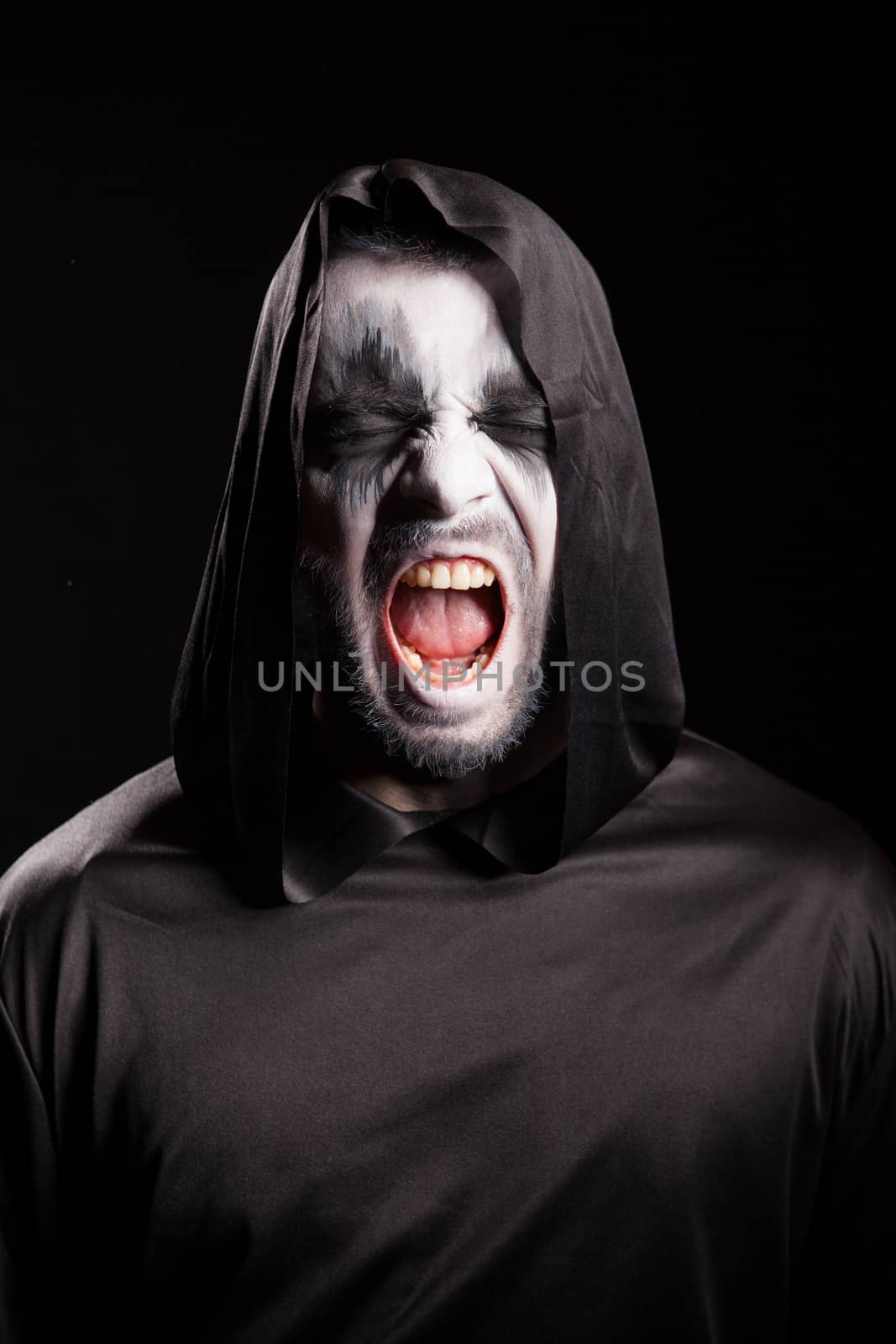 Portrait of grim reaper screaming over black background. Halloween costume.