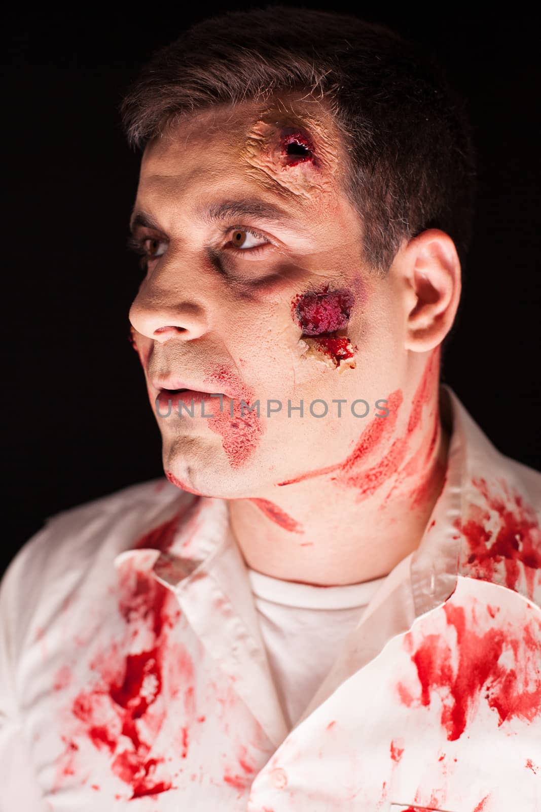 Close up bloody zombie over black background. Scary man. Creative makeup.