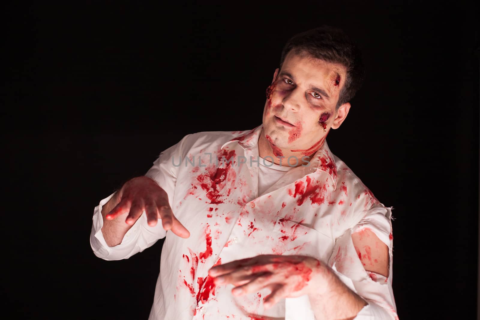 Man with bloody scars possessed by demon over black background for halloween. Creative makeup.