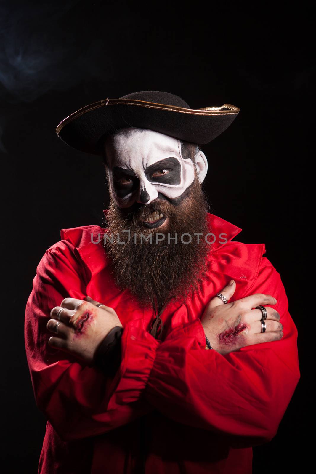 Bearded man in pirate outfit wearing spooky makeup over black background for halloween.