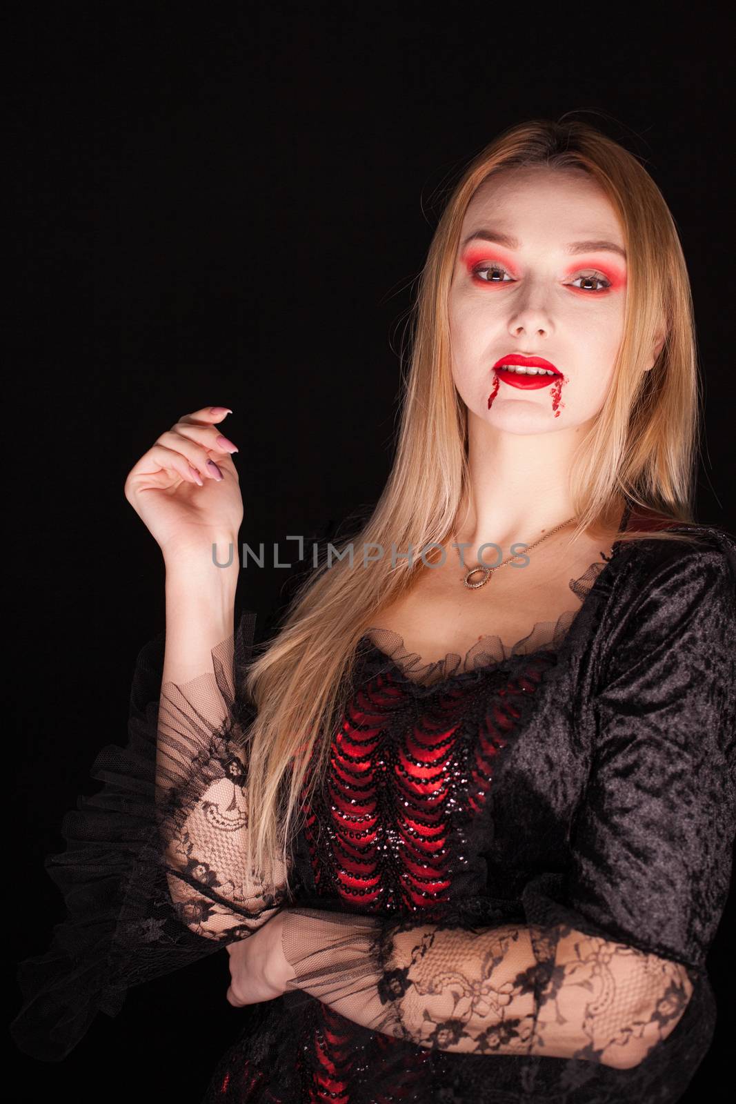 Vampire beautiful woman with bloody lips over black background by DCStudio
