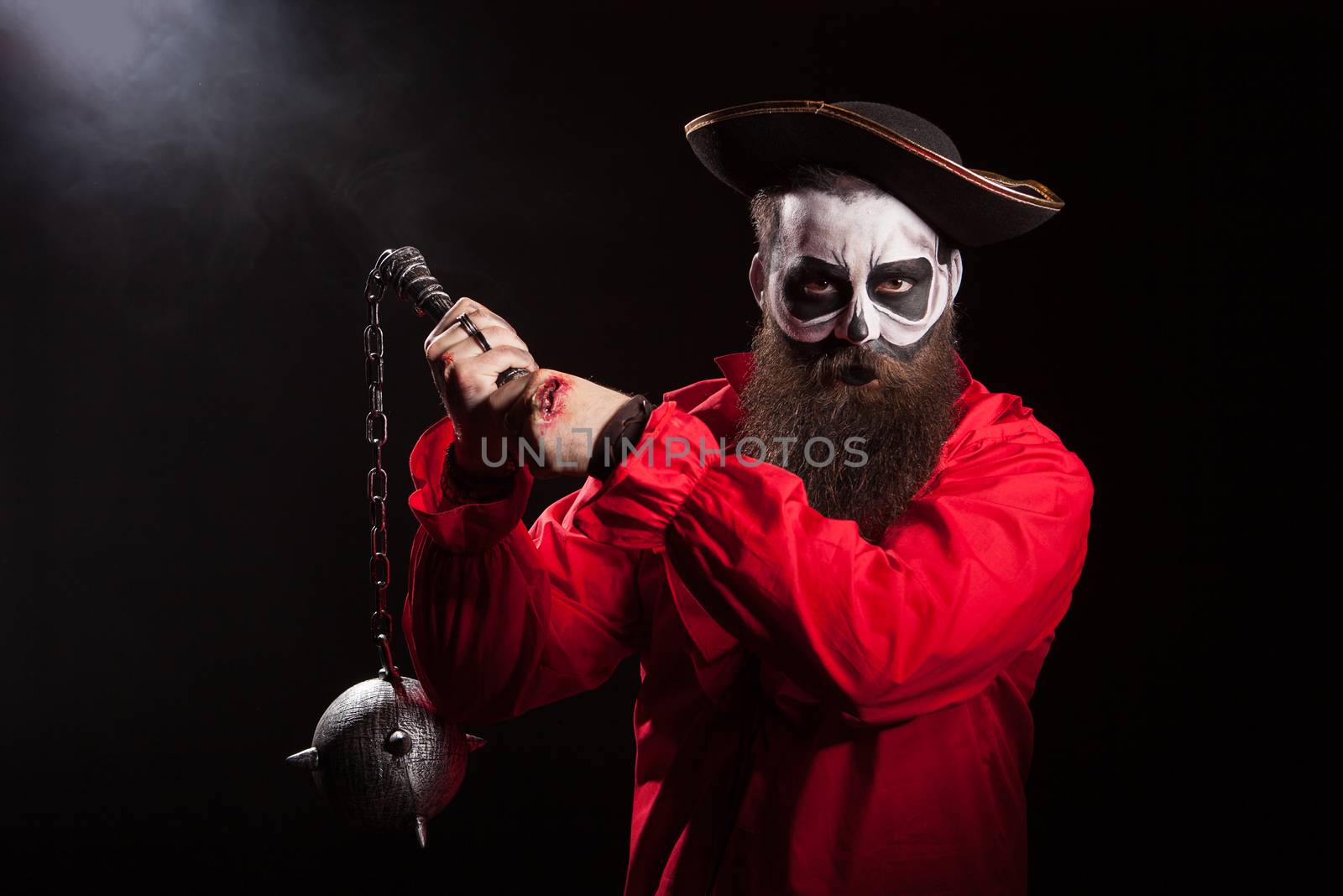 Spooky male pirate with long beard holding a mace over black background. Halloween outfit.