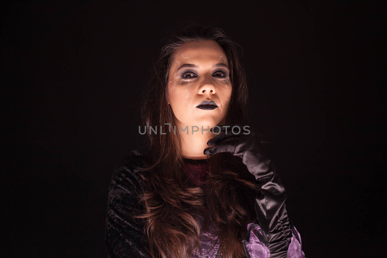Portrait of beautiful woman dressed up like a witch over black background.