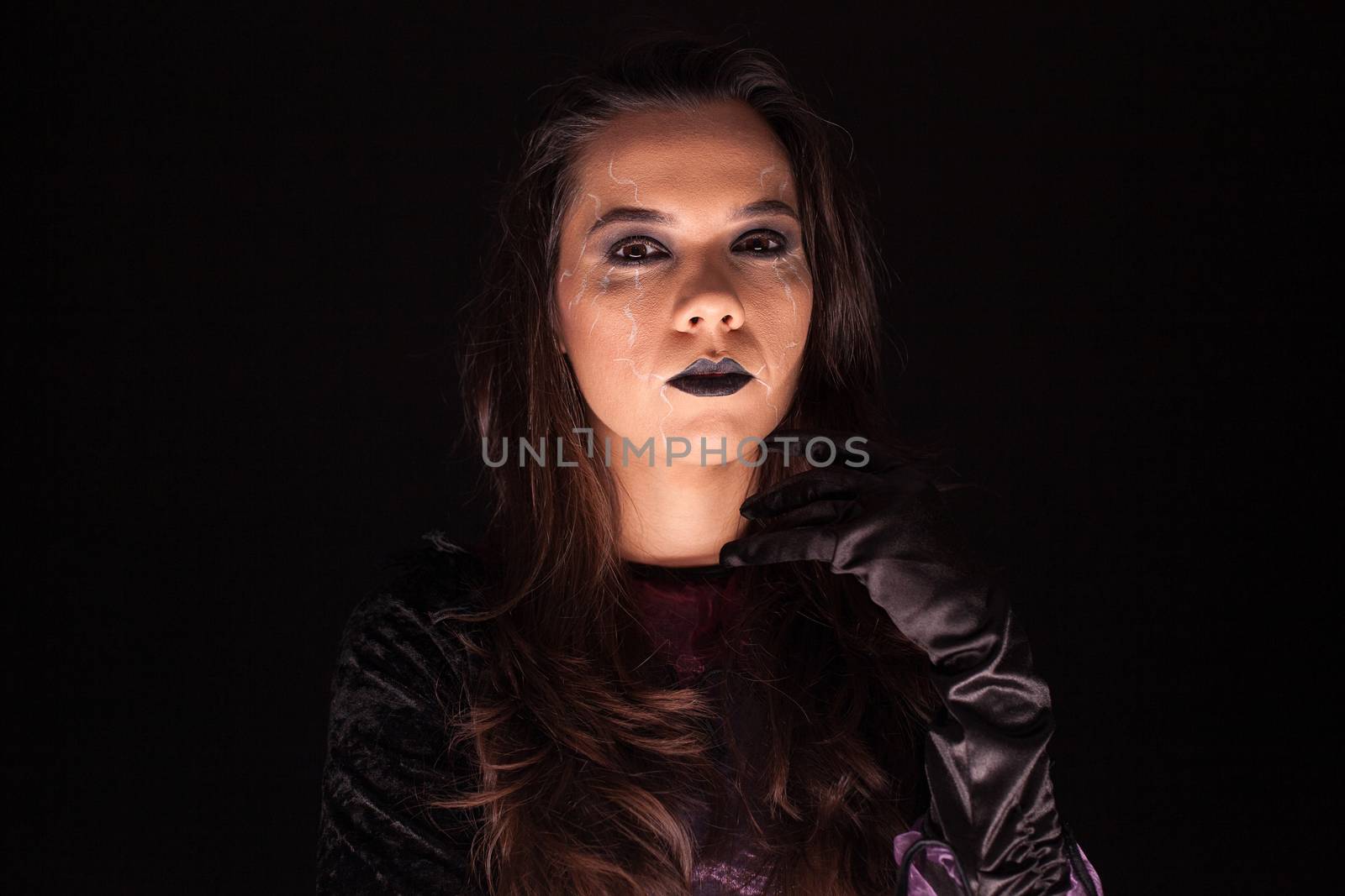 Lady wearing a witch costume over black background. Scary girl. Halloween outfit.