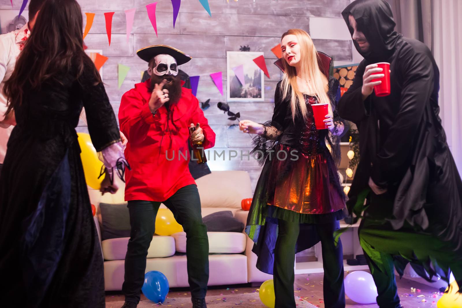 Attractive vampire woman with bloody lips celebrating halloween with her funny friends.