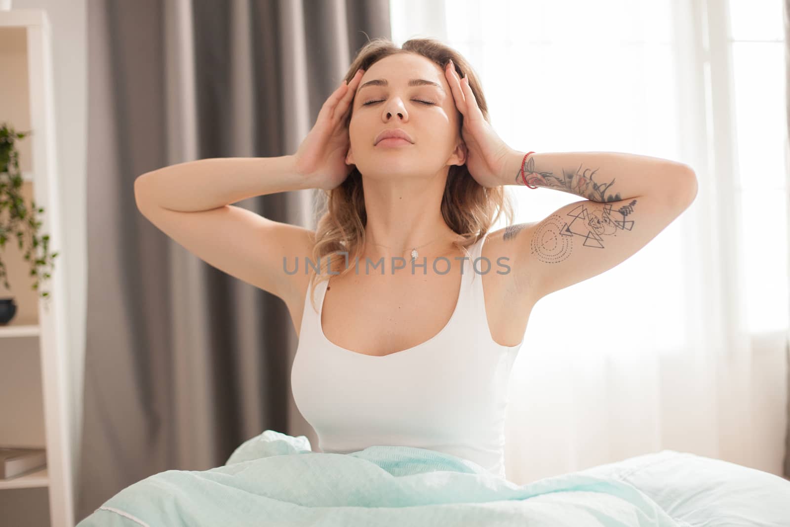 Pretty caucasian woman stretching in the morning after waking up wearing pajamas.