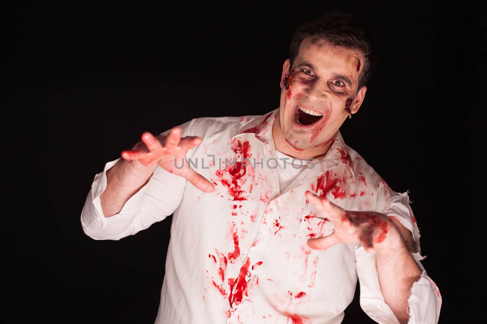 Person possessed by a zombie covered in blood over black background. Halloween costume.