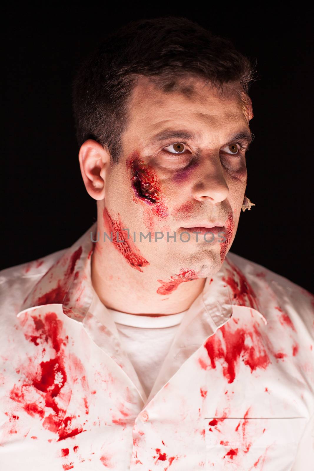 Close up of spooky zombie covered in blood over black background. Creative makeup.