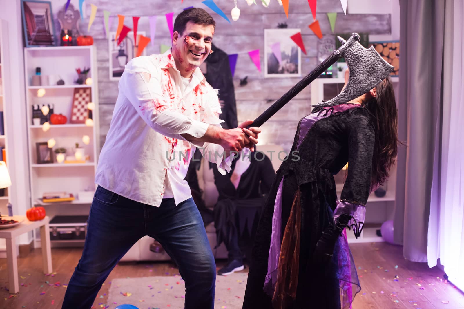 Man dressed up like zombie with an axe trying to kill an evil witch at halloween party.