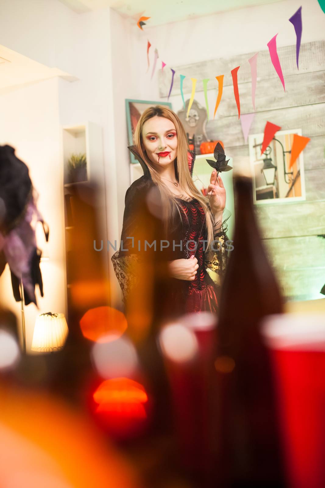 Portrait of beautiful vampire woman with bloody lips at halloween celebration.